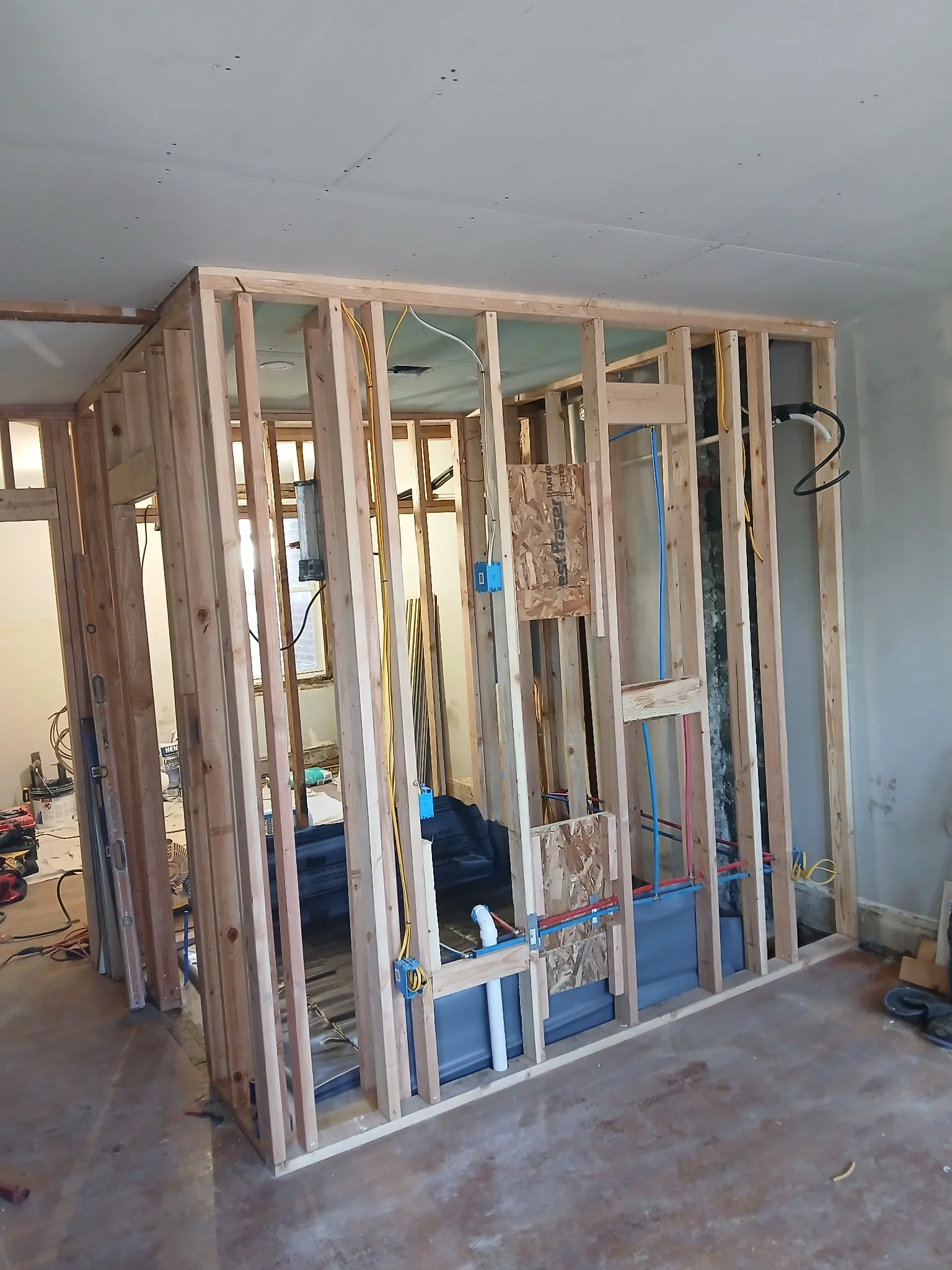 Wooden studs framing around shower pan with plumbing rough-in and electrical wiring for Full Bathroom Remodel