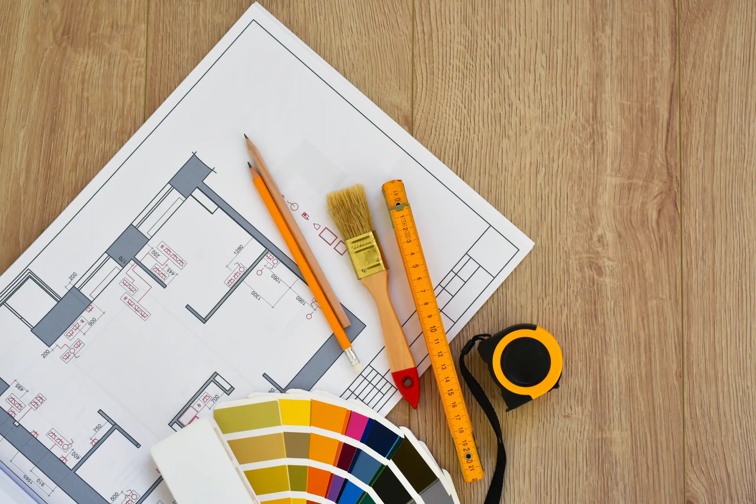 Custom Remodeling planning with floor plan, color swatches, pencil, paintbrush, ruler and tape measure on wooden table