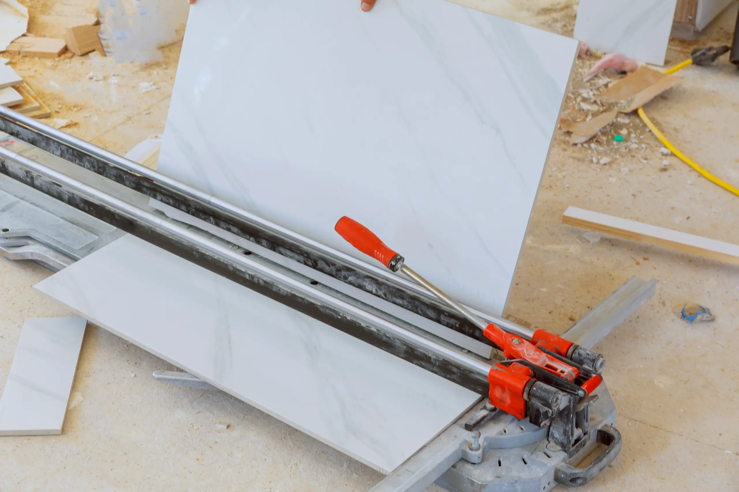 Manual tile cutter trimming large white floor tile – Tile Work