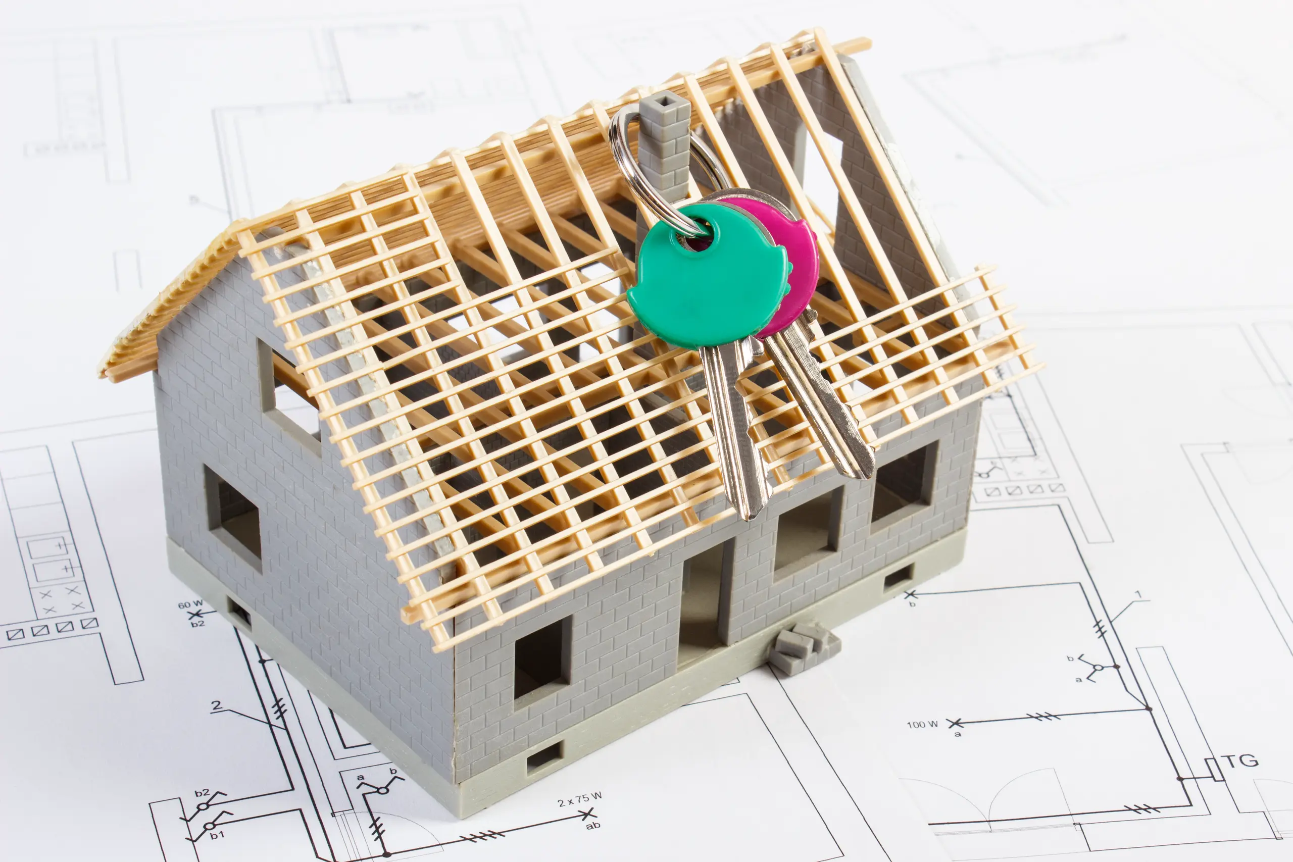 Model house framing atop architectural blueprints with keys indicating Structural Framing service