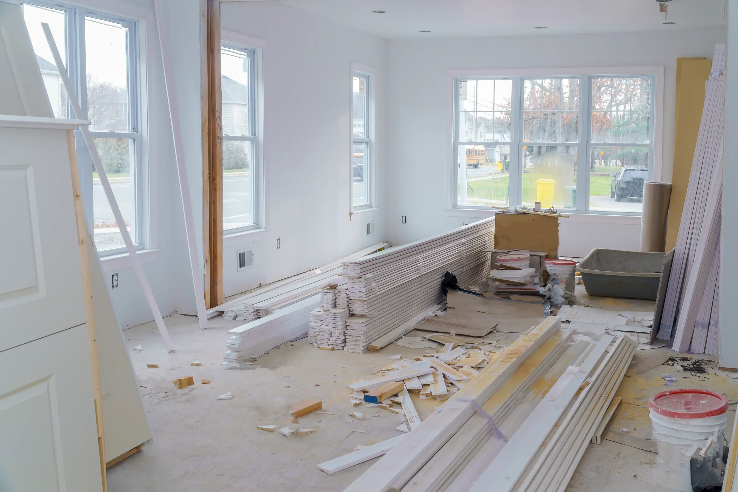 Interior living space during renovation, exposed studs, stacked trim boards, paint buckets, drywall and flooring materials Home Renovation
