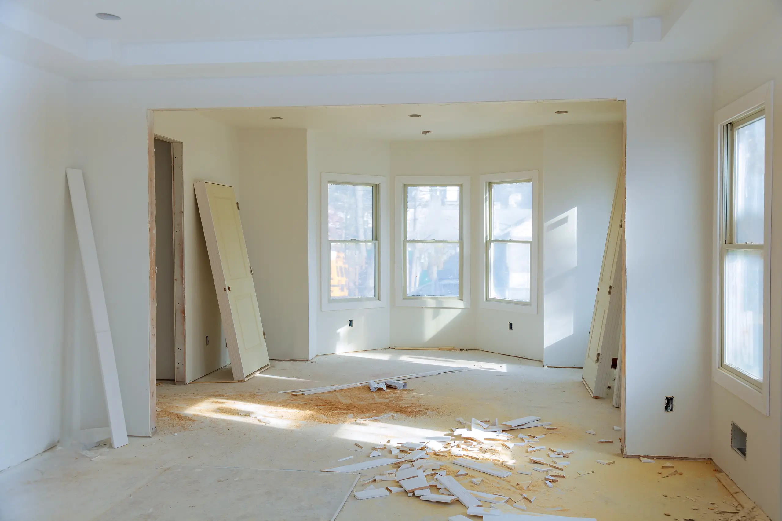 Interior room renovation showing Wall Removal with exposed subfloor and drywall scraps
