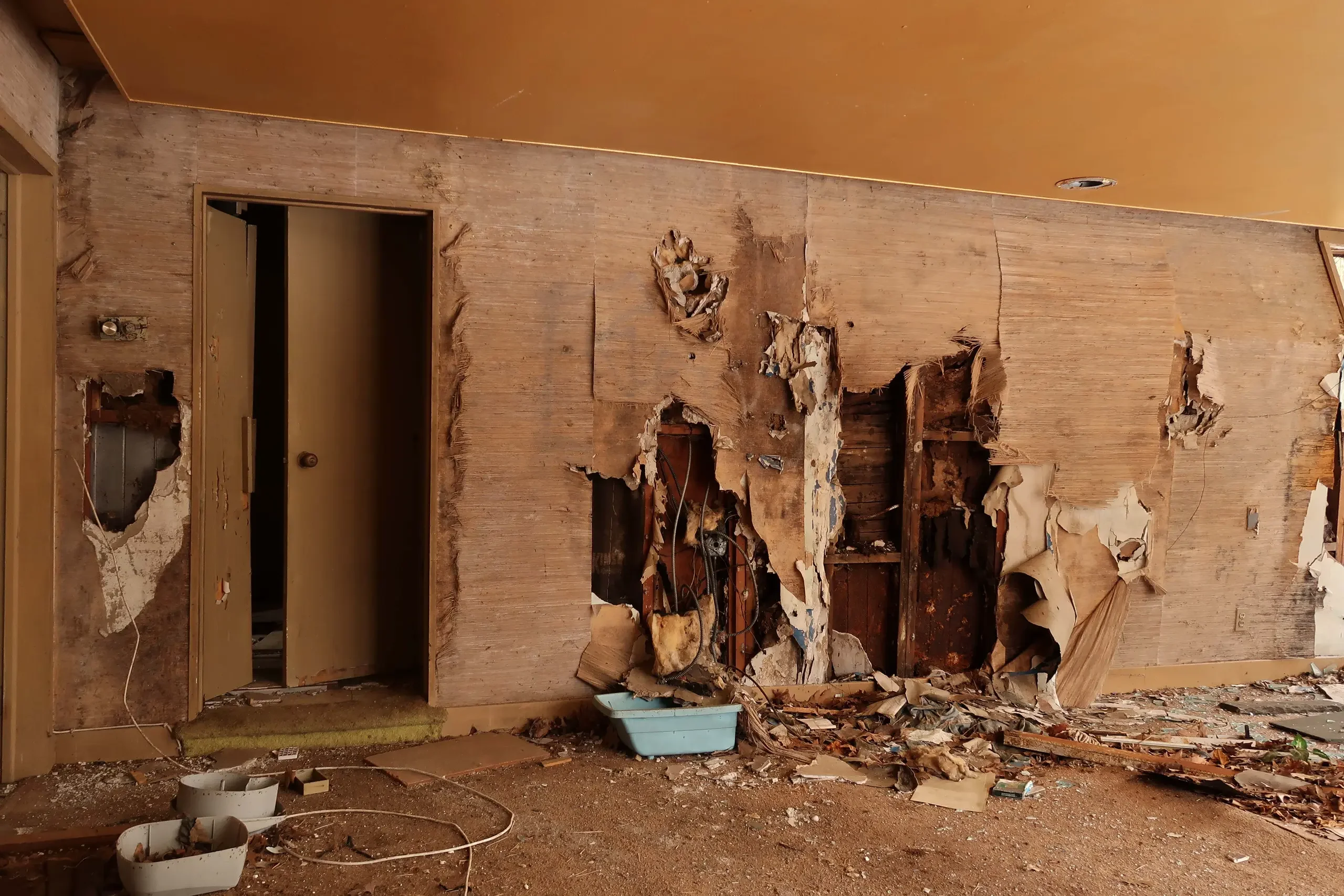 Interior wall demolition with damaged drywall and exposed studs for water damage repair