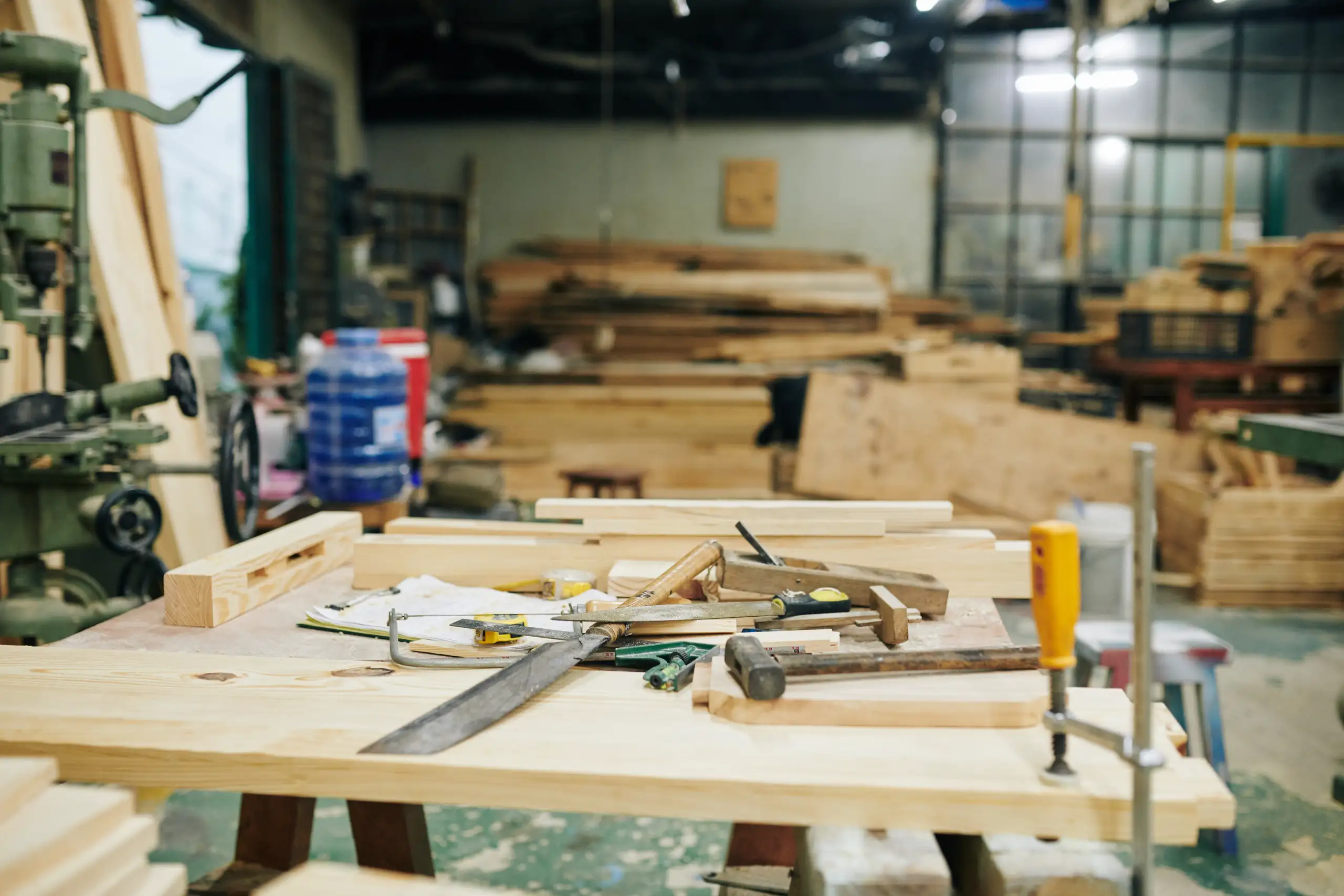Carpentry workbench with clamps, hand saw, hammer and wooden boards ready for fine carpentry