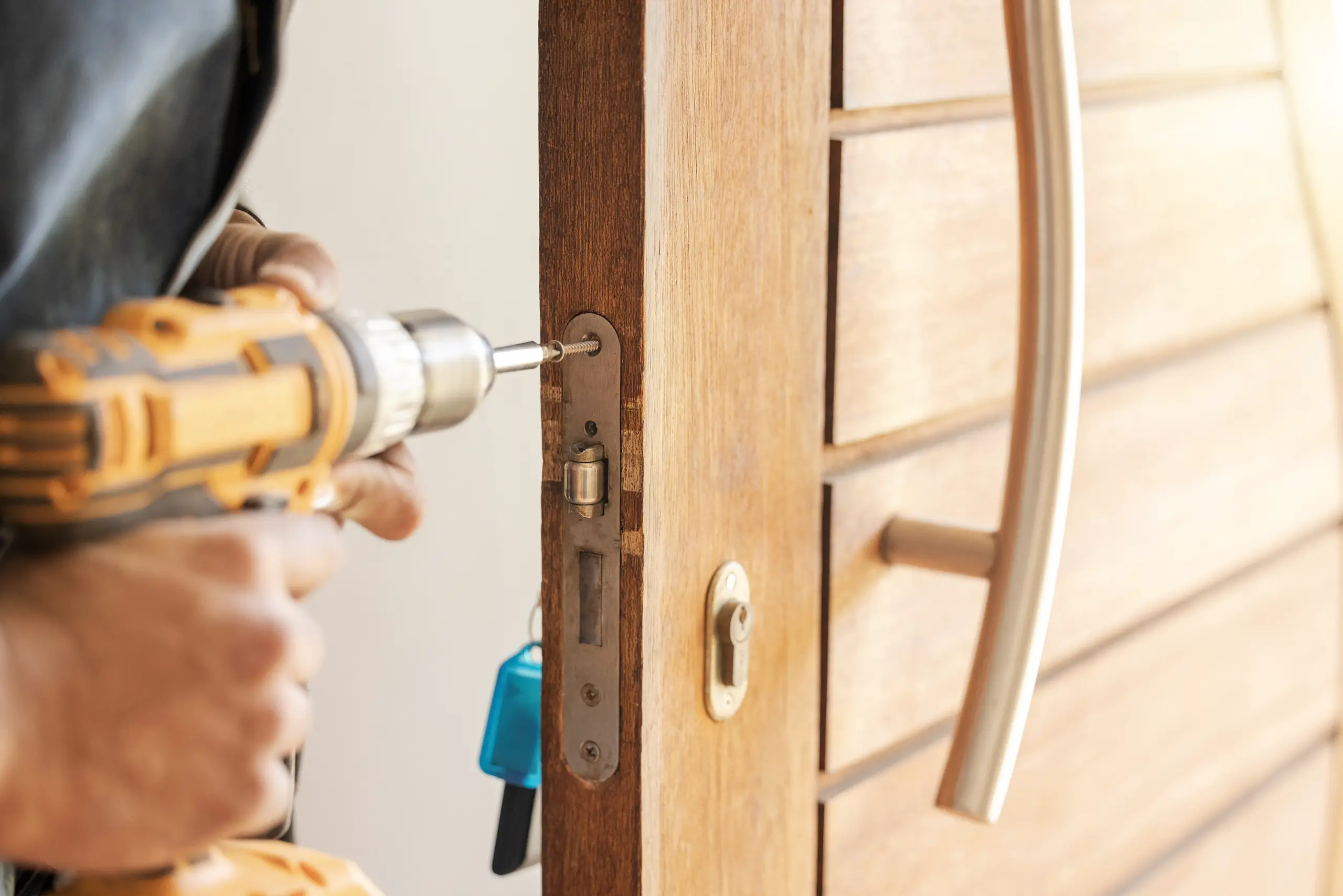 Technician drilling screws into wooden front door frame during door installation