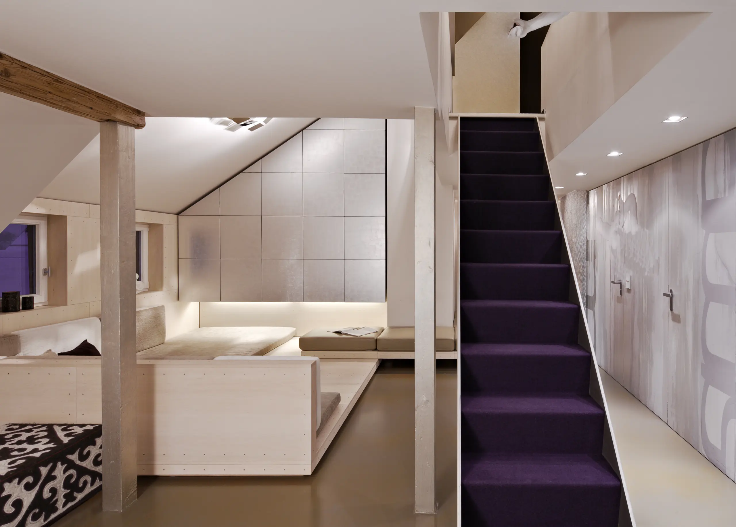 Modern attic space with built-in benches, purple-carpeted staircase, light wood flooring and white walls after Full Home Remodel