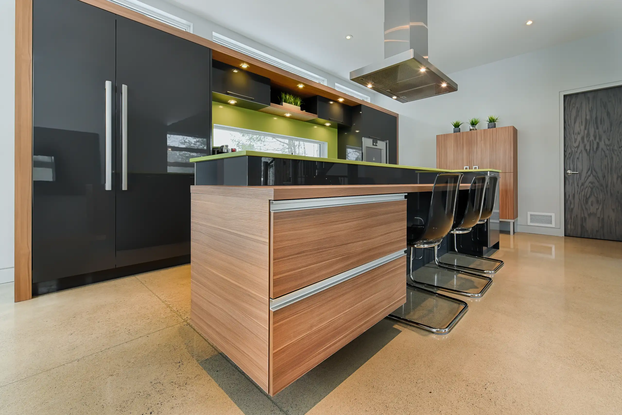 Modern kitchen interior with wood and black gloss island, green countertop accent and bar stools Custom Kitchen Remodel