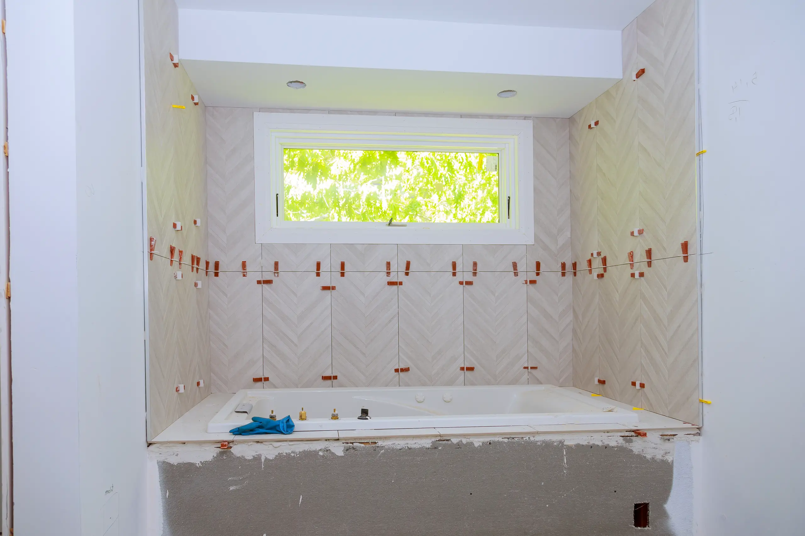 Herringbone tile installation around bathtub with spacers during Tile Work