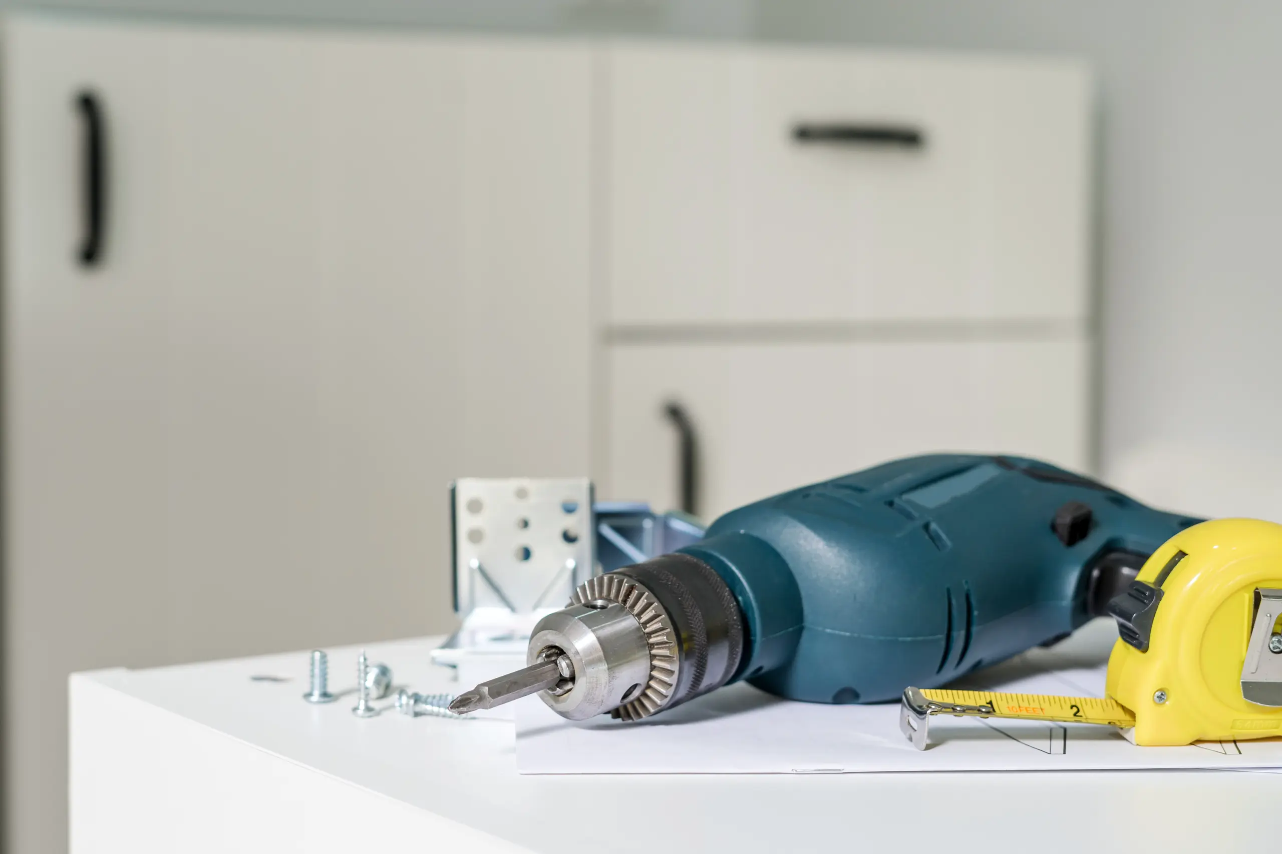 Power drill, measuring tape and screws on countertop for Home Improvement