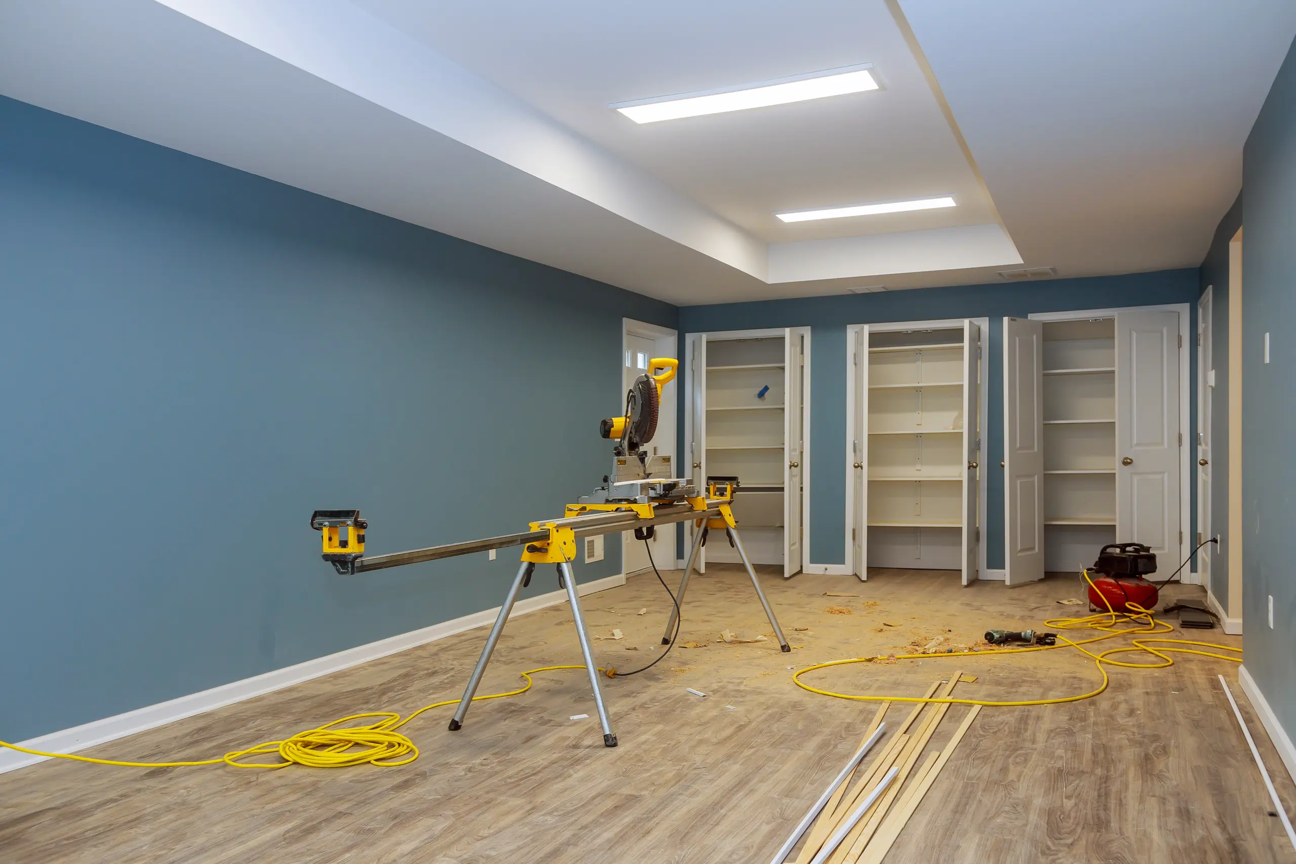Saw and flooring materials in a blue-painted room under Basement Finishing