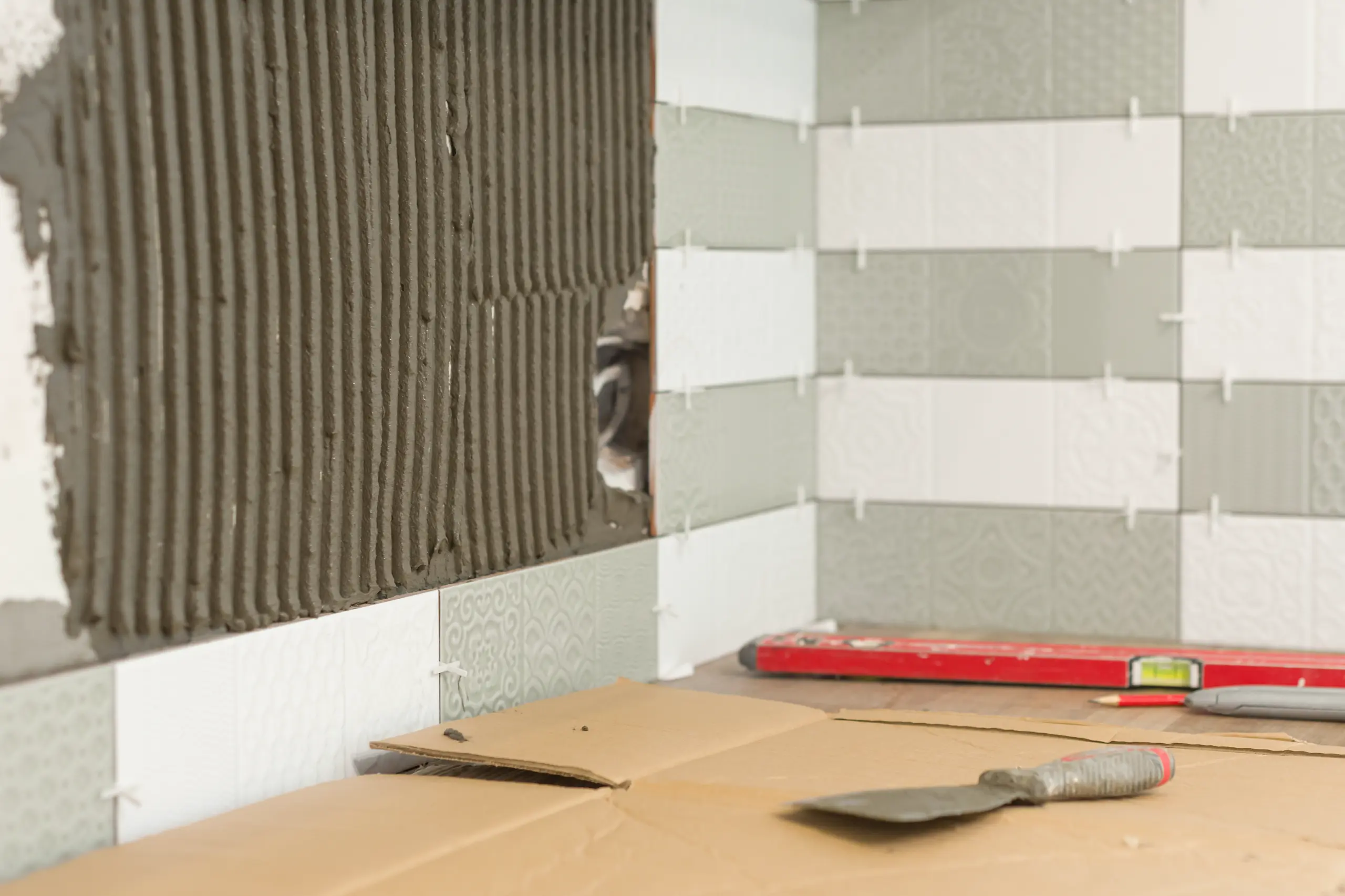 Kitchen backsplash tile setting with adhesive mortar, spacers, trowel and level