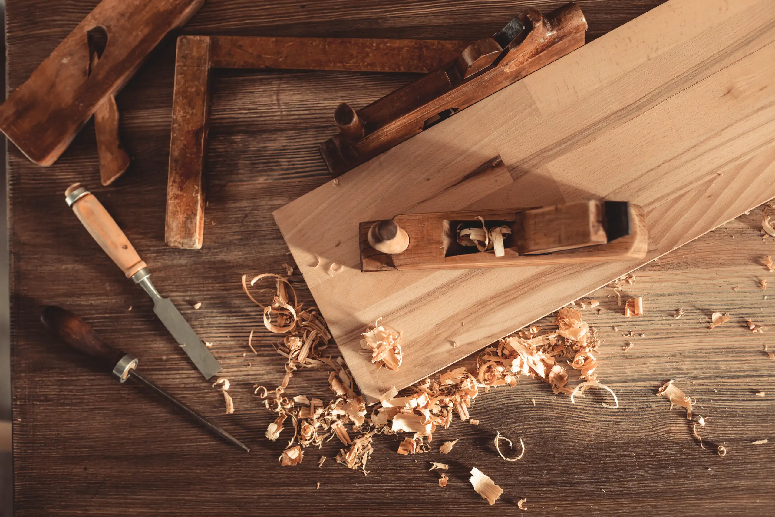 Hand plane, chisels and wood shavings on a workbench during Fine Carpentry